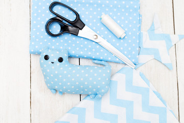 Blue toy cat sewn by hand on a white wooden background. Handmade