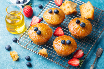 Muffins,cakes with fresh berries and honey on cooling rack