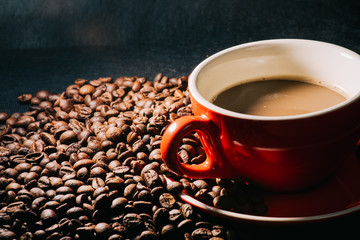 coffee in red cup and coffee beans are the background.