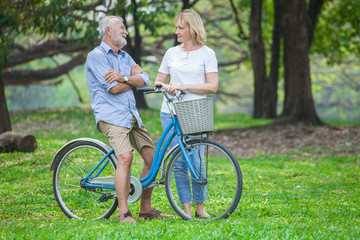 Obraz premium happy Senior Couple in a park with a bicycle