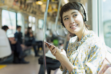 電車で音楽を聴く女性