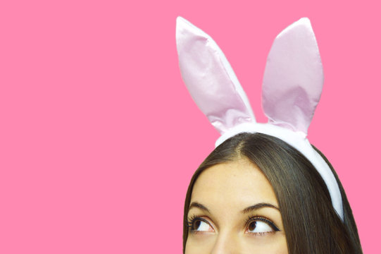 Female with bunny ears looking copy space isolated on pink background
