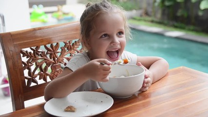 mother and daughter sitting at table, son coming back from barbecue with plate full of fresh grilled food