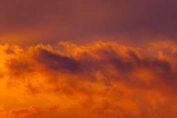 Beautiful view of a dark clouds in the orange sky illuminated by the rising sun