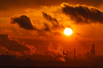 Sunset or sunrise against the background of the city and smoking chimneys