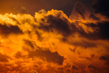 Fototapeta premium Dramatic view of a dark silhouettes of clouds in the orange sky illuminated by sunrise (background)