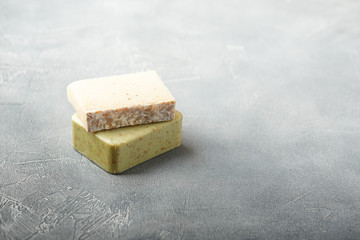Two pieces of handmade soap on a gray background