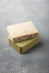 Two pieces of handmade soap on a gray background