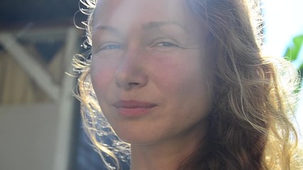 Portrait of an attractive middle-aged woman. He looks and smiles at the camera. Behind the setting sun beautifully highlights her hair