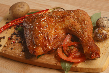 Appetizing fried chicken leg with spices and herbs, on a rustic background.