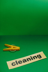 Cleaning house or office concept. Green clothes peg, Cleaning inscription on a green background. Top view, closeup