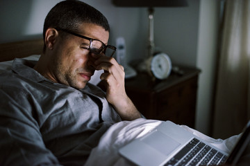 Man using laptop on a bed