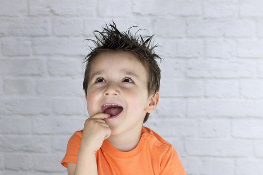 ni&ntilde;o peque&ntilde;o mirando hacia arriba con cara de sorpresa y un dedo en la boca