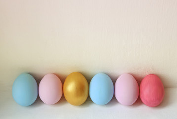 A row of pastel colored Easter eggs on white background. Festive easter background in minimalism style.