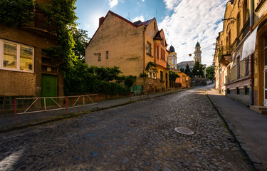 Fototapeta na wymiar empty street of old town on summer morning. cobblestone pavement on the ground. beautiful scenery with architecture of Austria-Hungary times.