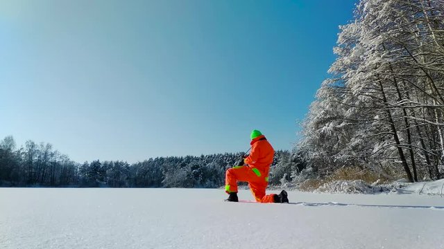 Photographer making a photo on the surface of frozen lake
