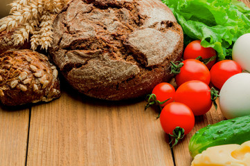 Mixed vegetables and two breads on wooden table