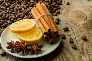 Coffee beans with cinnamon and anise and lemon on wooden board