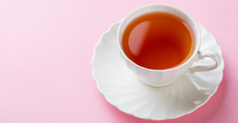 Tea in white cup on pink background. Copy space.