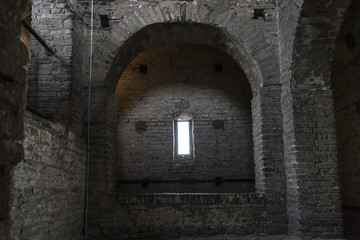 Fototapeta na wymiar Stone interior with window of an old steeple crypt, located inside an ancient catholic church