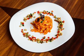 A horizontal image of pasta linguine with sauce and ratatouille on a white plate. Selective focus.