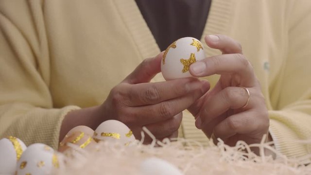 man rolling an easter iegg in hands. egg in golden stars