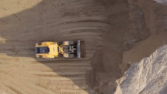 Aerial view loading bulldozer in open air quarry.