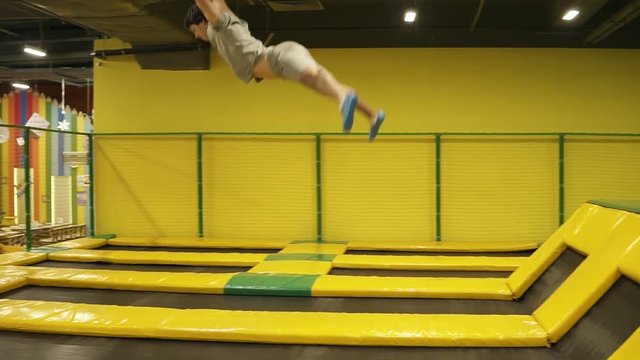 Young sportive boy having the time of his life enjoying jumping on trampoline. Performing handspring flips.