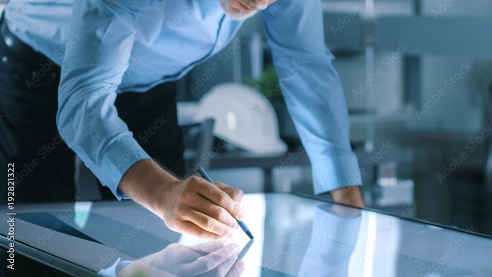 Aufkleber Senior Architectural Engineer Draws Building Concept on a Graphics Tablet Display Vertical Touchscreen Table. Clean Minimalistic Office, Concrete Walls Covered by Blueprints.