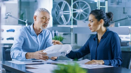 Experienced Automotive Designer and Female Engineer Works with a Concept Car Prototype Model, Perfecting it and Making Design Corrections. They Work in a Stylish, Bright, Modern Office.