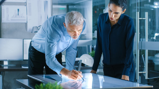 Senior Male and Young Female Architectural Designers Draw Building Concept on a GraphicsTablet Display Vertical Touchscreen Table. - Powered by Adobe