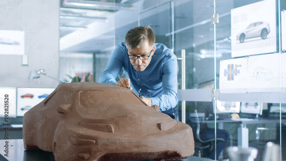 Poster experience automotive designer with a rake sculpts prototype car model from plasticine clay. he work