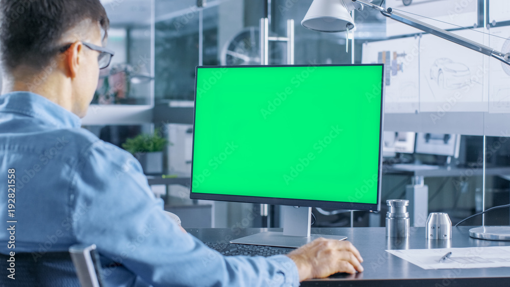 Aufkleber Automotive Engineer Working on a Personal Computer With Isolated Mock-up Green Screen on it. He Works in the Bright and Modern Office with Car Sketches on the Walls.