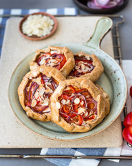 Mini pizza, vegetable galette with cream cheese, red onion, tomatoes, sweet pepper and almonds