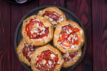 Mini pizza, vegetable galette with cream cheese, red onion, tomatoes, sweet pepper and almonds