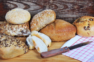 fresh wheat and rye buns with sesame seeds, linseed and pumpkin seeds and sunflower seeds cut with knife