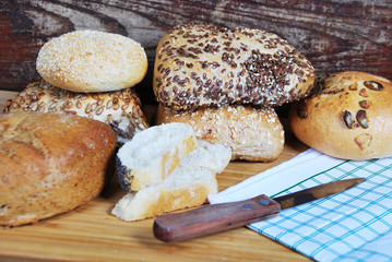 fresh wheat and rye buns with sesame seeds, linseed and pumpkin seeds and sunflower seeds cut with knife