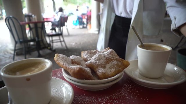 A waiter drops off water to compliment a beignet with coffee in New Orleans