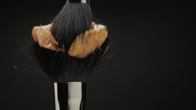 black brush with a liquid foundation and another brush smudge it
