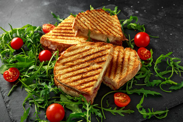 Grilled Bacon, cheese sandwich and served on stone platter with arugula and tomatoes