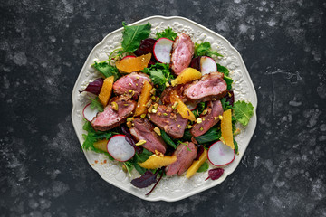 Duck breast fillets steak salad with orange halves, radishes and crushed pistachios