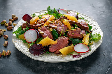 Duck breast fillets steak salad with orange halves, radishes and crushed pistachios