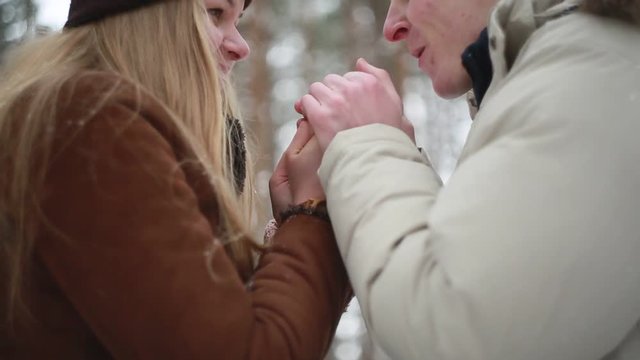 A young man warms hands in winter girl 