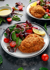 Breaded Chicken Kiev breast stuffed with butter, garlic and herbs served with vegetables in a plate.