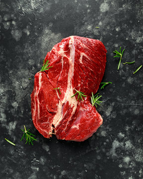 Fresh Raw braising steak on black background with rosemary