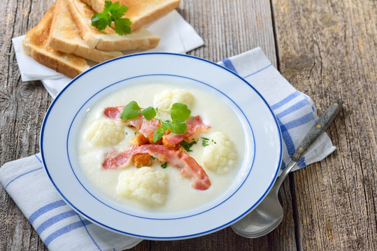 Delikate Blumenkohl-Cremesuppe  mit gebratenen Speckstreifen und Croutons, serviert mit knusprigem Weizentoast &ndash; Cauliflower cream soup topped with fried bacon and croutons, served with crisp toast