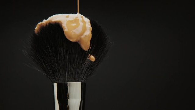 black brush with a liquid foundation pouring on it