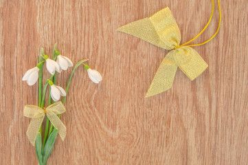 Bouquet of snowdrops with a bow on a wooden table