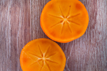 Two halves of persimmon on a wooden table