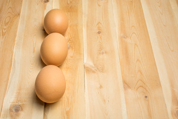 Three chicken eggs lie on a wooden board